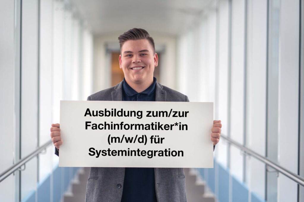 Azubi hält Schild hoch mit Stellenbeschreibung